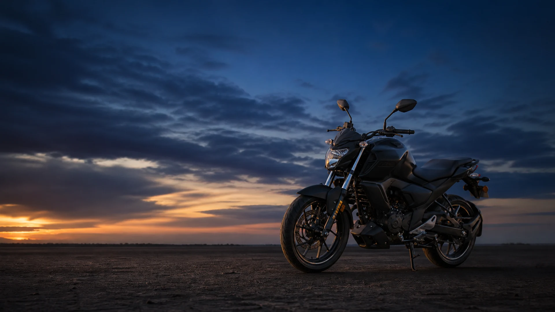 Black geared motorcycle on open ground at dusk